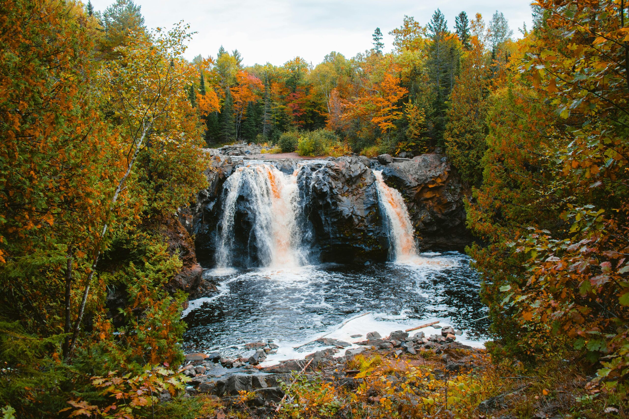 Explore the stunning waterfall surrounded by vibrant autumn foliage in Wisconsin's serene forest.